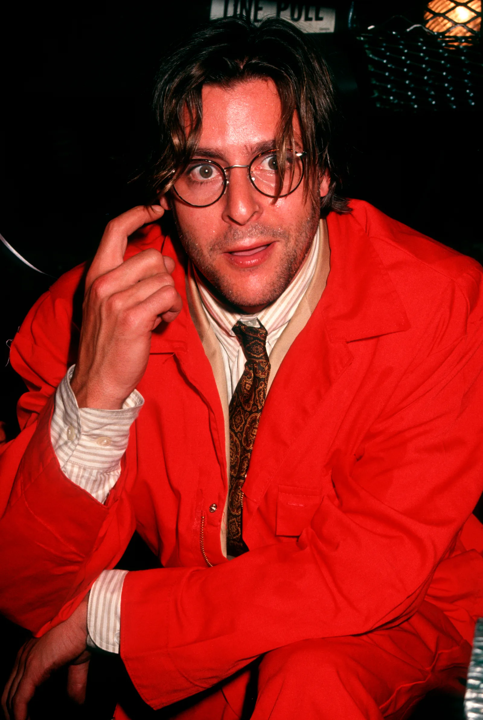 Striking a playful pose in a vibrant red jumpsuit paired with round-framed glasses and a patterned tie, the actor celebrated the premiere party for "The Dark Backward" at The Gas Station in New York City.