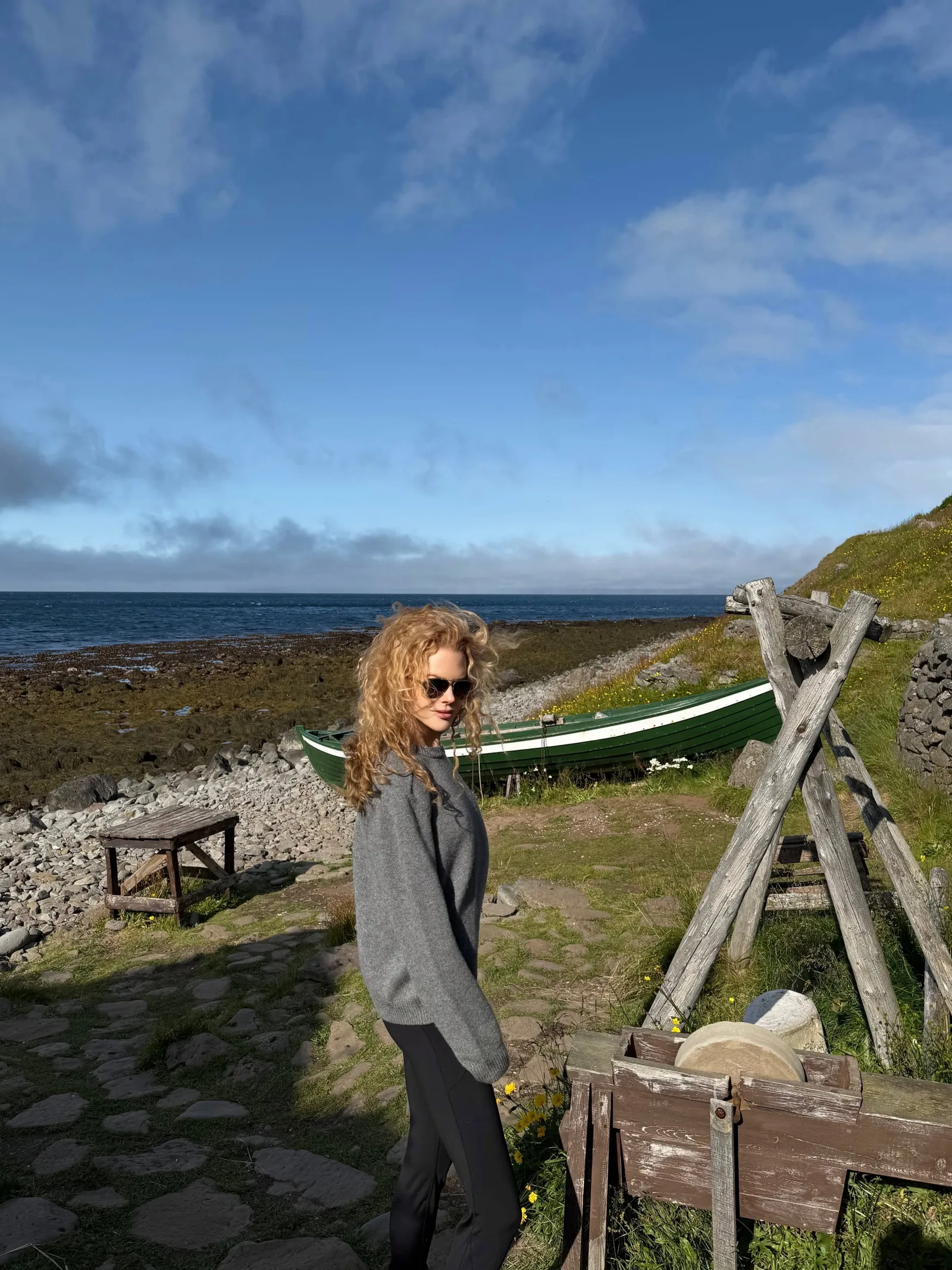 Soaking in the rugged Icelandic landscape, Nicole poses in sunglasses and a relaxed sweater along the stony shoreline. Her voluminous '90s-style ringlets took center stage against the dramatic coastal backdrop.