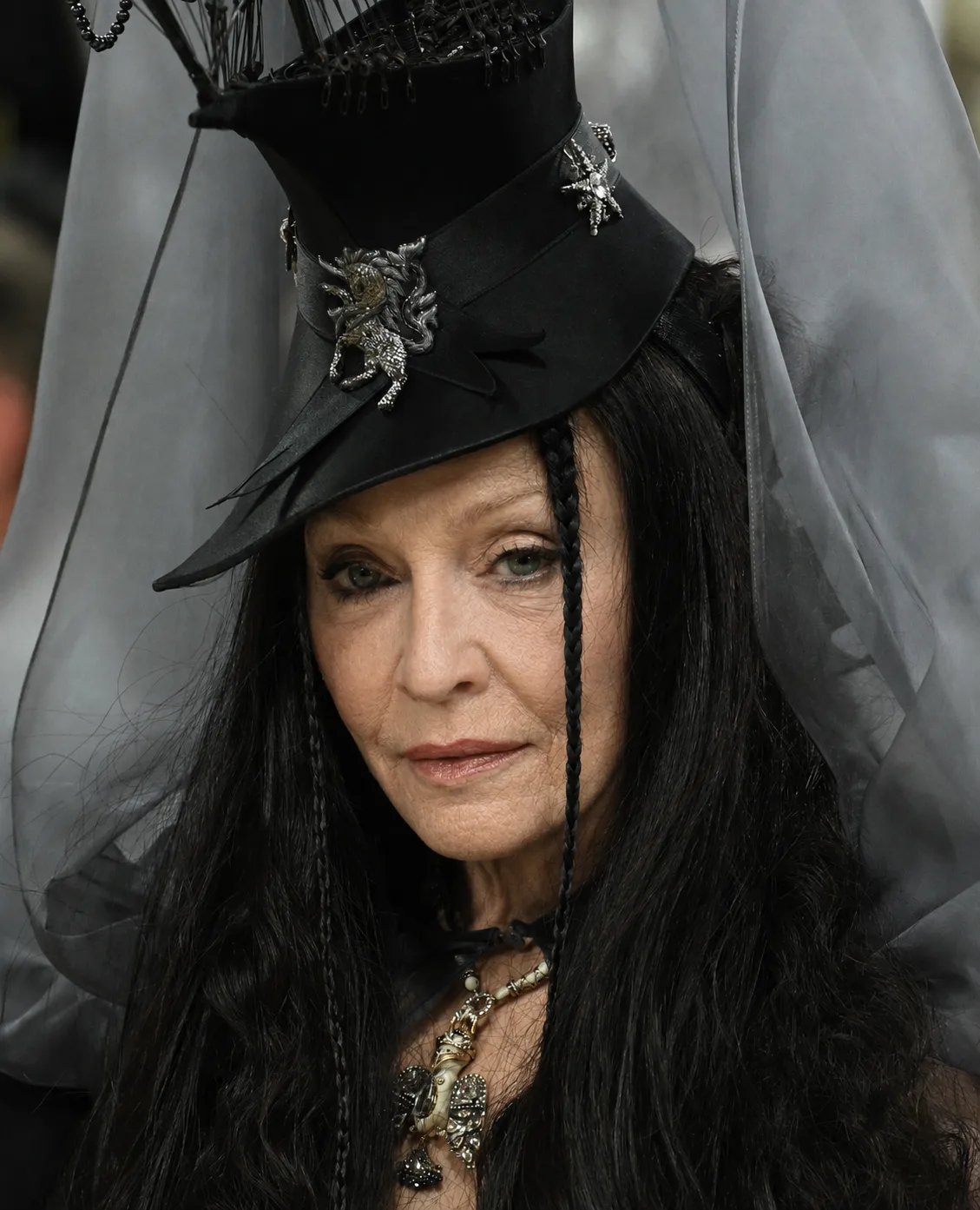 The digitally reworked portrait preserves Madonna's dramatic hat, veil and dark hair while imagining a more visibly aged facial appearance.