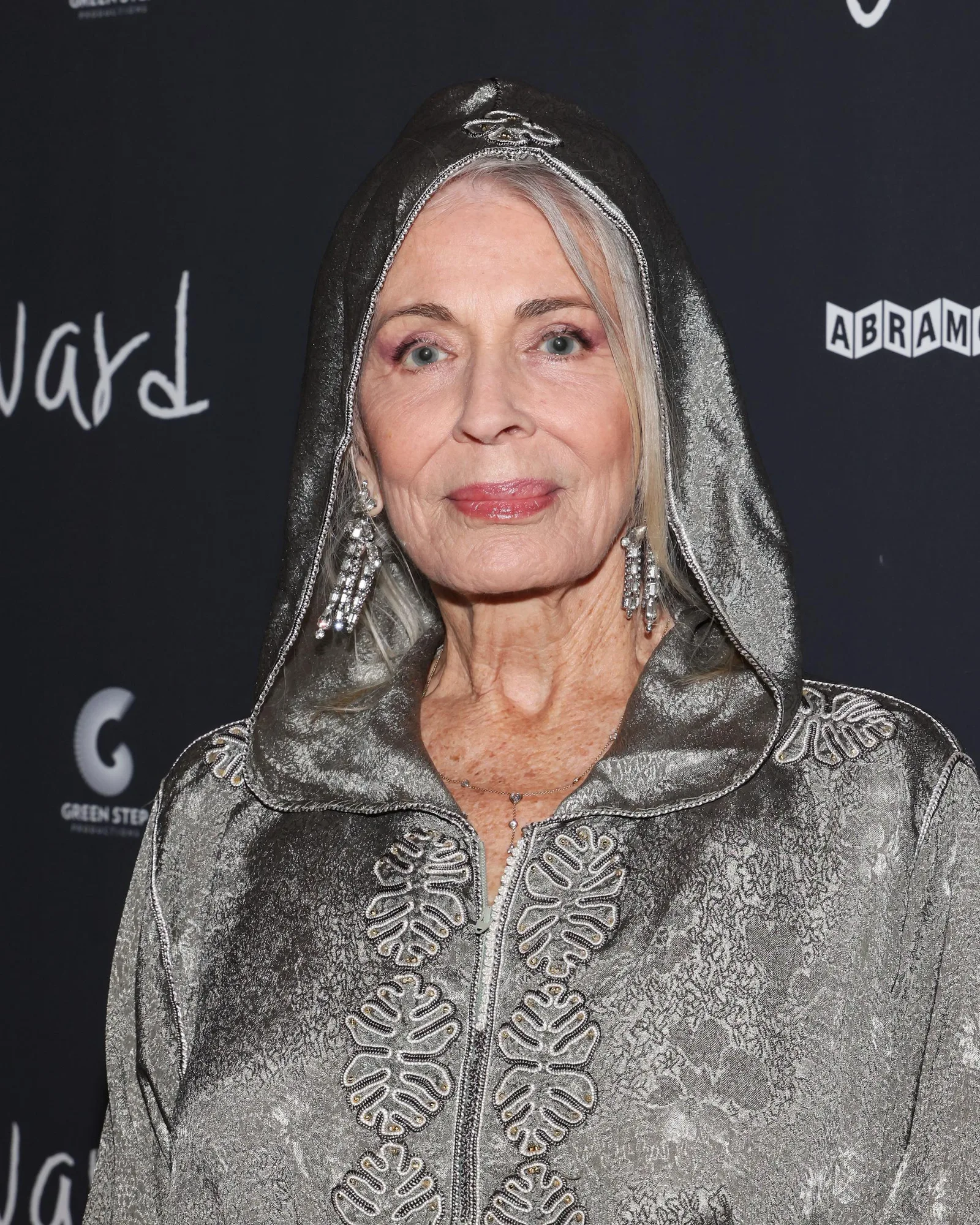 Joanna Cassidy attends the 2024 Los Angeles premiere of "Wayward" in a metallic hooded ensemble with embroidered detailing and statement earrings. The appearance highlights the veteran actress's distinctive red carpet style.