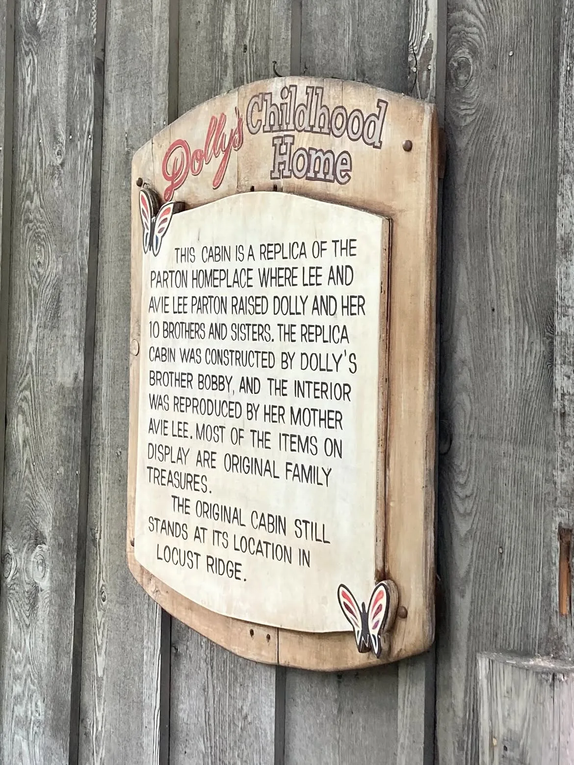The Dollywood display explains that Dolly's brother Bobby constructed the replica while their mother, Avie Lee, reproduced its interior. It also notes that many items displayed inside are original Parton family treasures and that the real cabin remains in Locust Ridge.