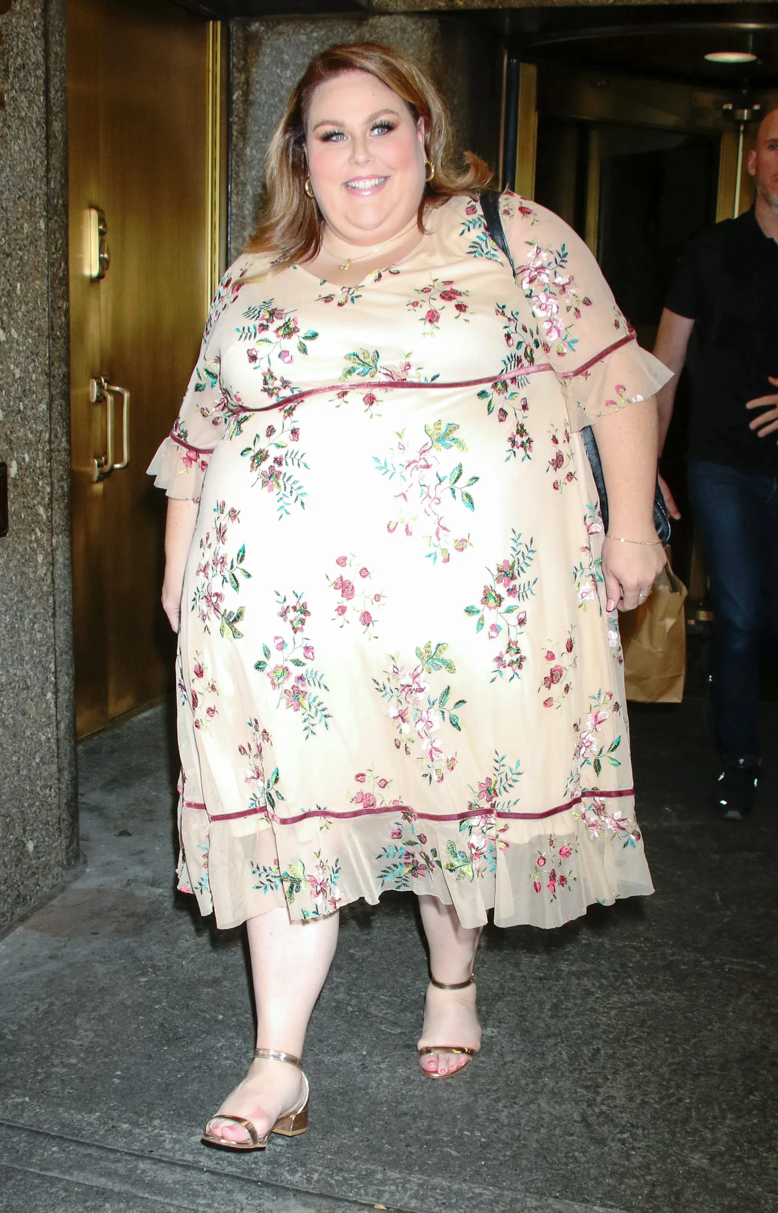 Metz was also photographed in New York wearing a light cream floral dress with pink and green prints. The street-style image provides a less formal look at her appearance during the same year.