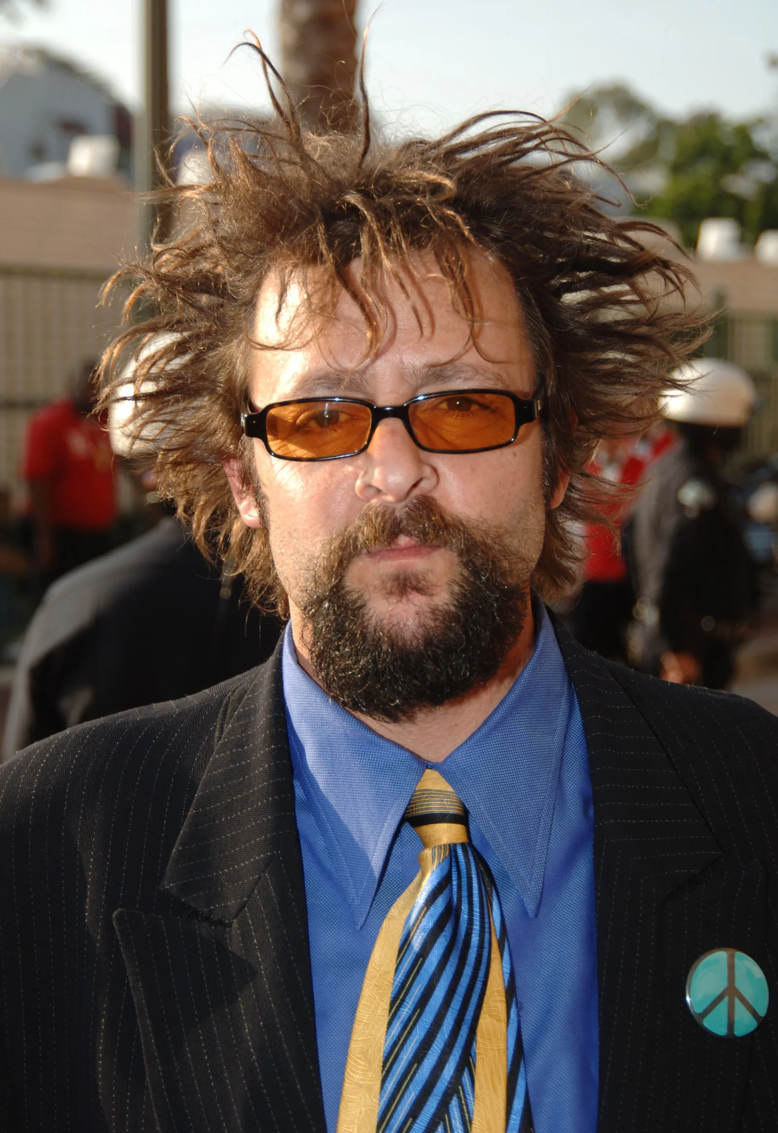 Sporting a distinctive spiky hairstyle, orange-tinted sunglasses, and a peace sign pin on his suit jacket, the star showcased a bold look on the red carpet at the 2005 MTV Movie Awards in Los Angeles.