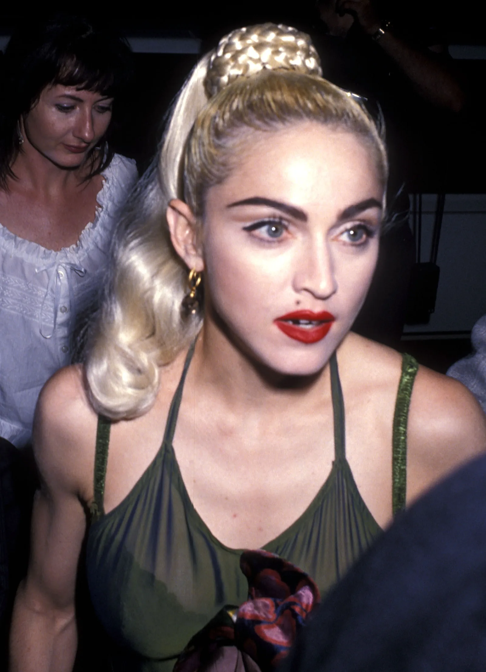 By 1990, Madonna was photographed with a high blond ponytail, sharply defined eye makeup, and bright red lipstick. The close-up reflects another distinct look in her evolving public image.