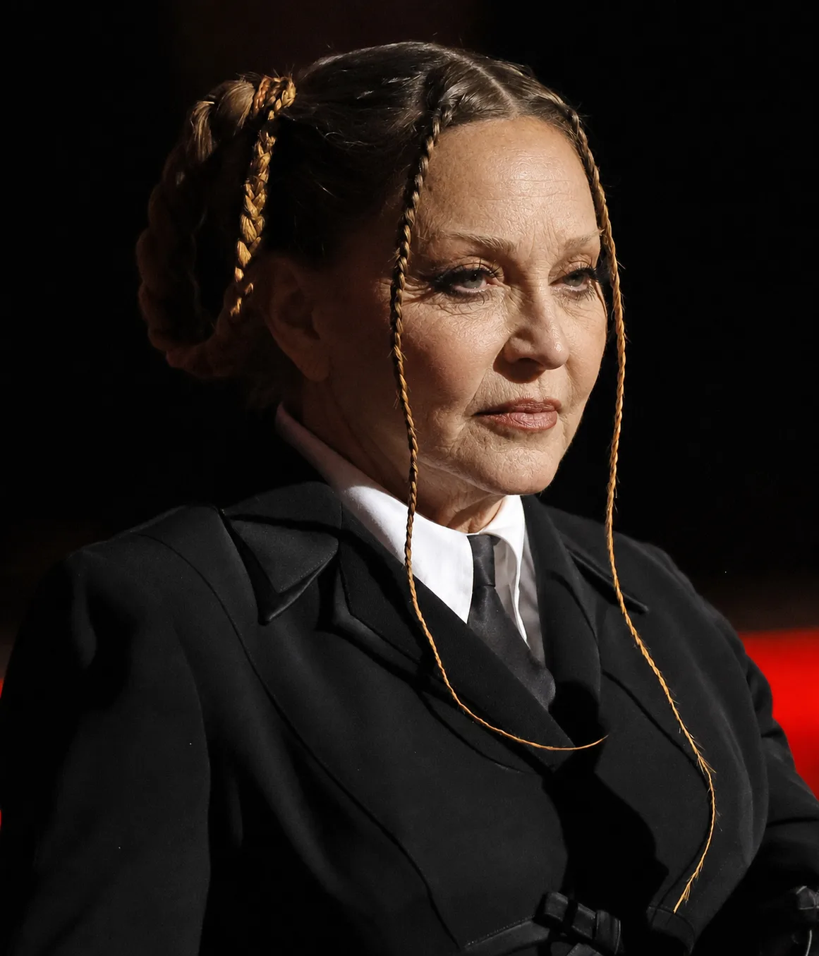 The AI interpretation keeps Madonna's structured black ensemble and braided hairstyle while giving her face more pronounced signs of aging.