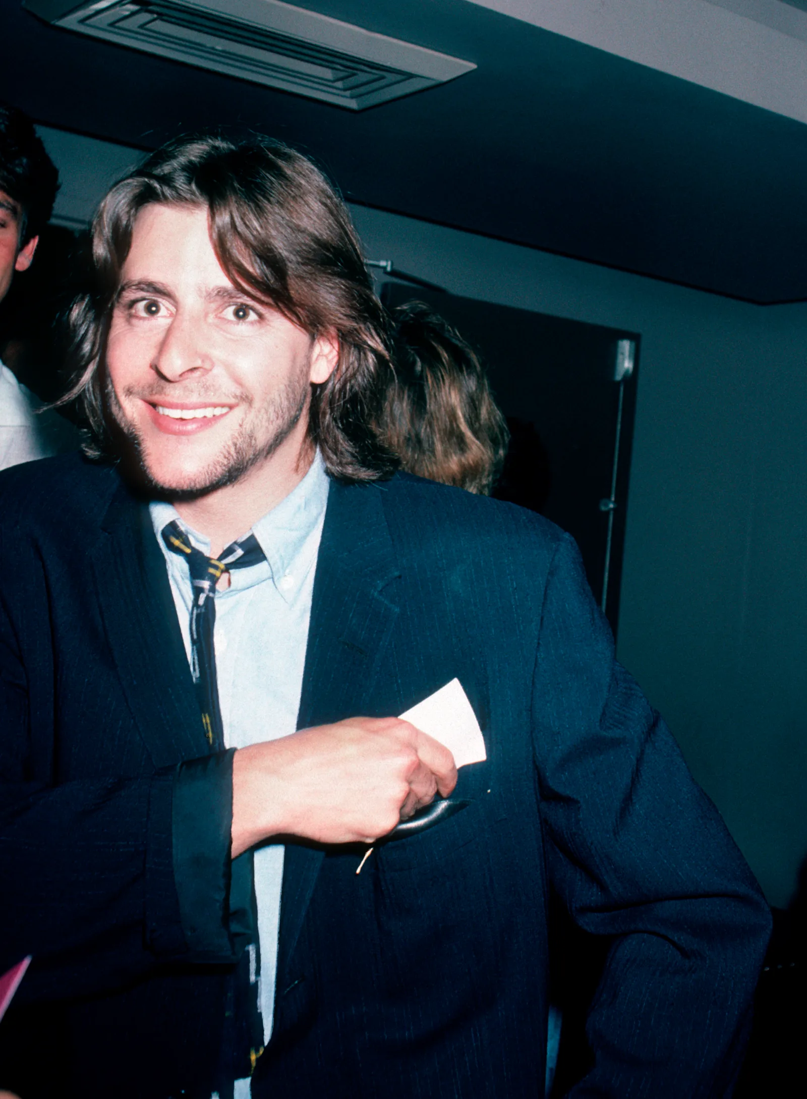 Flashing a warm smile while slipping a card into his jacket pocket, the young actor enjoyed an evening out at the Peter Max Art Exhibit at Marylou's in New York City in 1986.