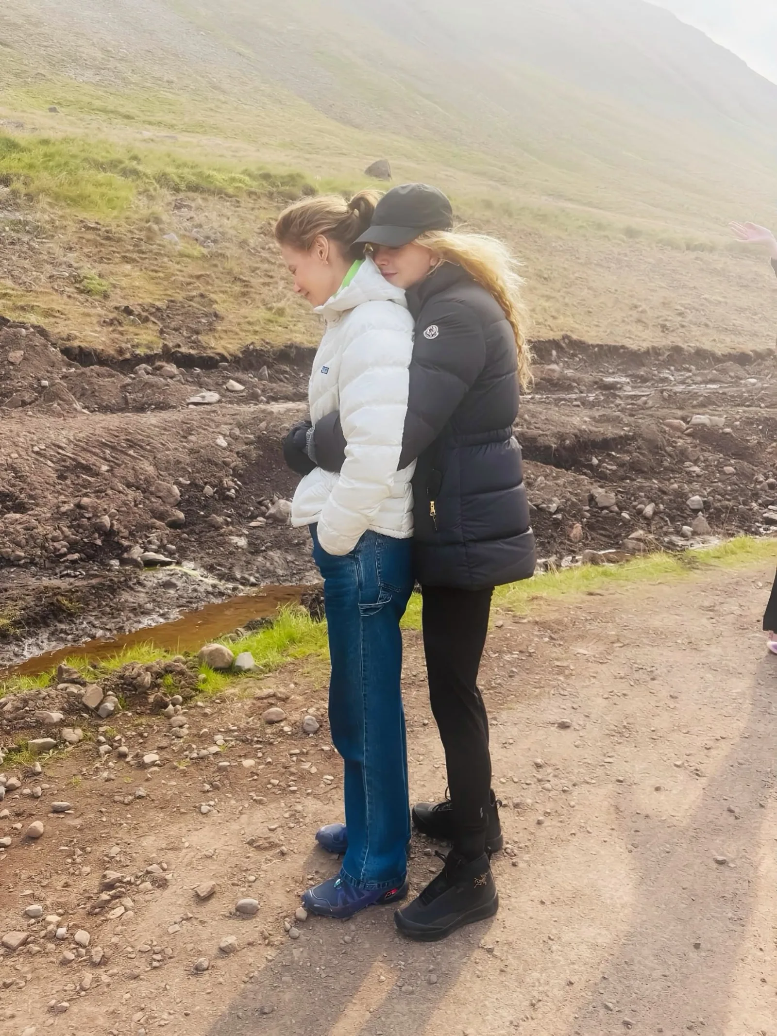 Nicole wraps her loved one in a tight embrace during an outdoor excursion. Wearing a dark padded coat and hat, her golden ringlets caught the mountain breeze.