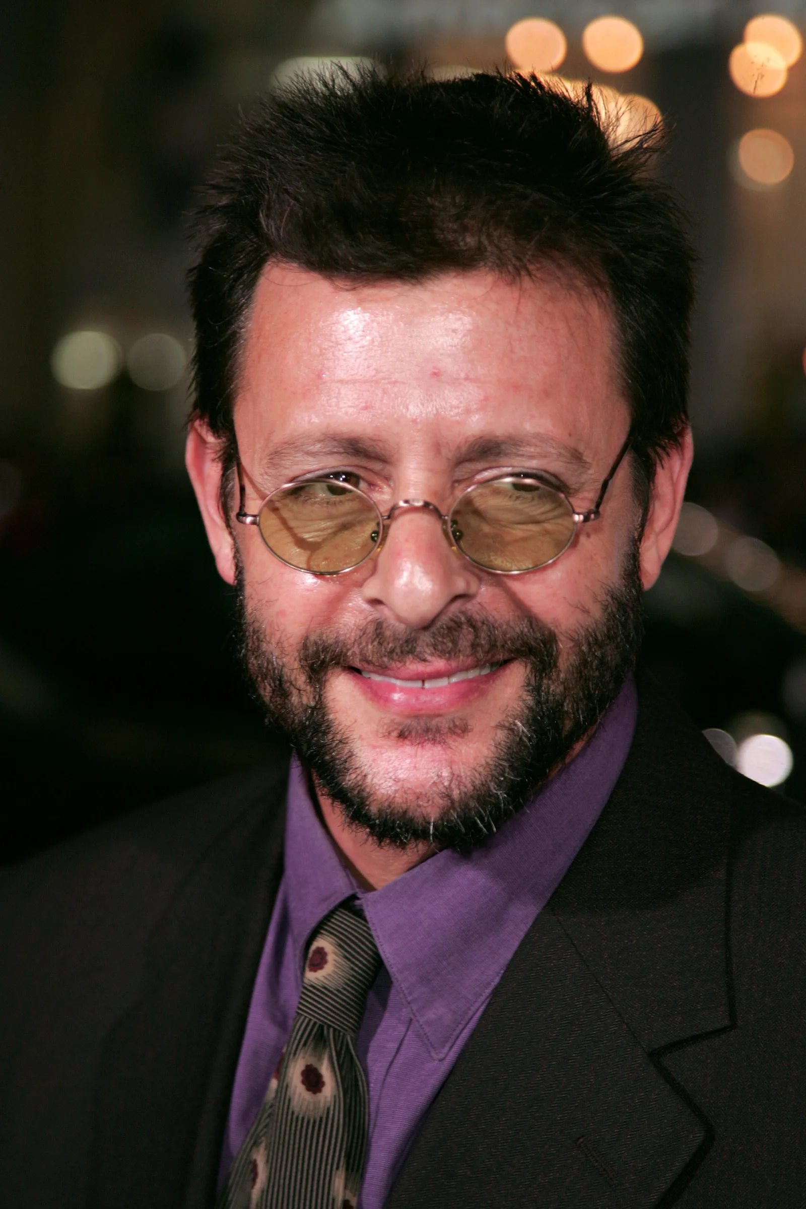 Wearing small round tinted glasses, a full beard, and a purple collared shirt with a patterned tie, the actor smiled warmly upon arriving at Grauman's Chinese Theatre for the Hollywood premiere of "Jackass: Number Two."