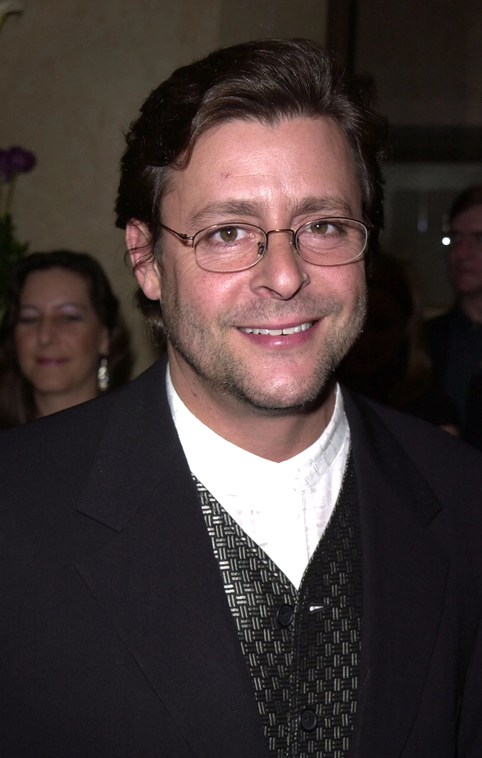 Wearing thin-framed glasses and a patterned vest beneath a dark jacket, the actor flashed a warm smile at the 15th Annual Genesis Awards on March 10, 2001.
